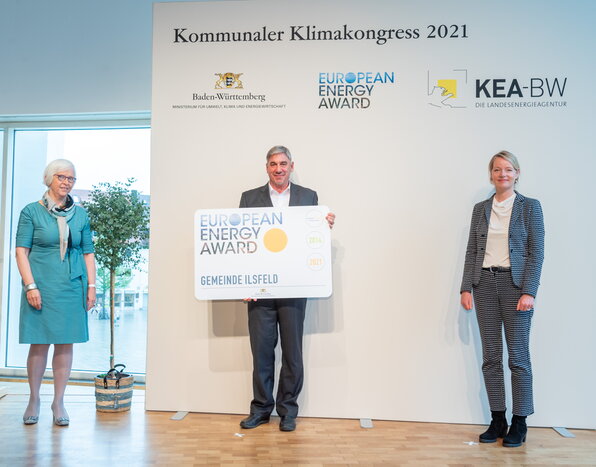 Quelle Bild: Umweltministerium BW / Martin Stollberg (v.l.n.r.:  Frau Heute-Bluhm (Präsidentin des europäischen Trägervereins Association European Energy Award AISBL), Herr Reiner Vogel (Stellvertretender Bürgermeister Gemeinde Ilsfeld), Frau Thekla Walker (Ministerin für Umwelt, Klima und Energiewirtschaft.))